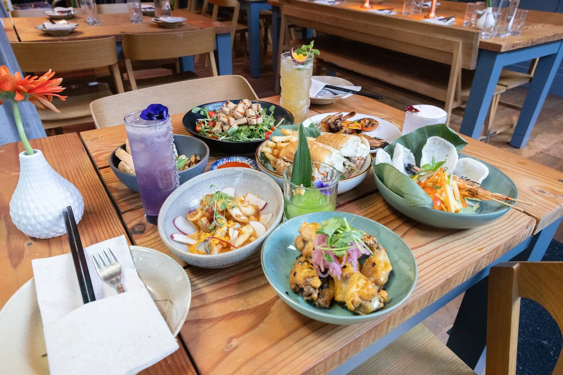 A full table at Xóm — multiple dishes and cocktails shared among friends