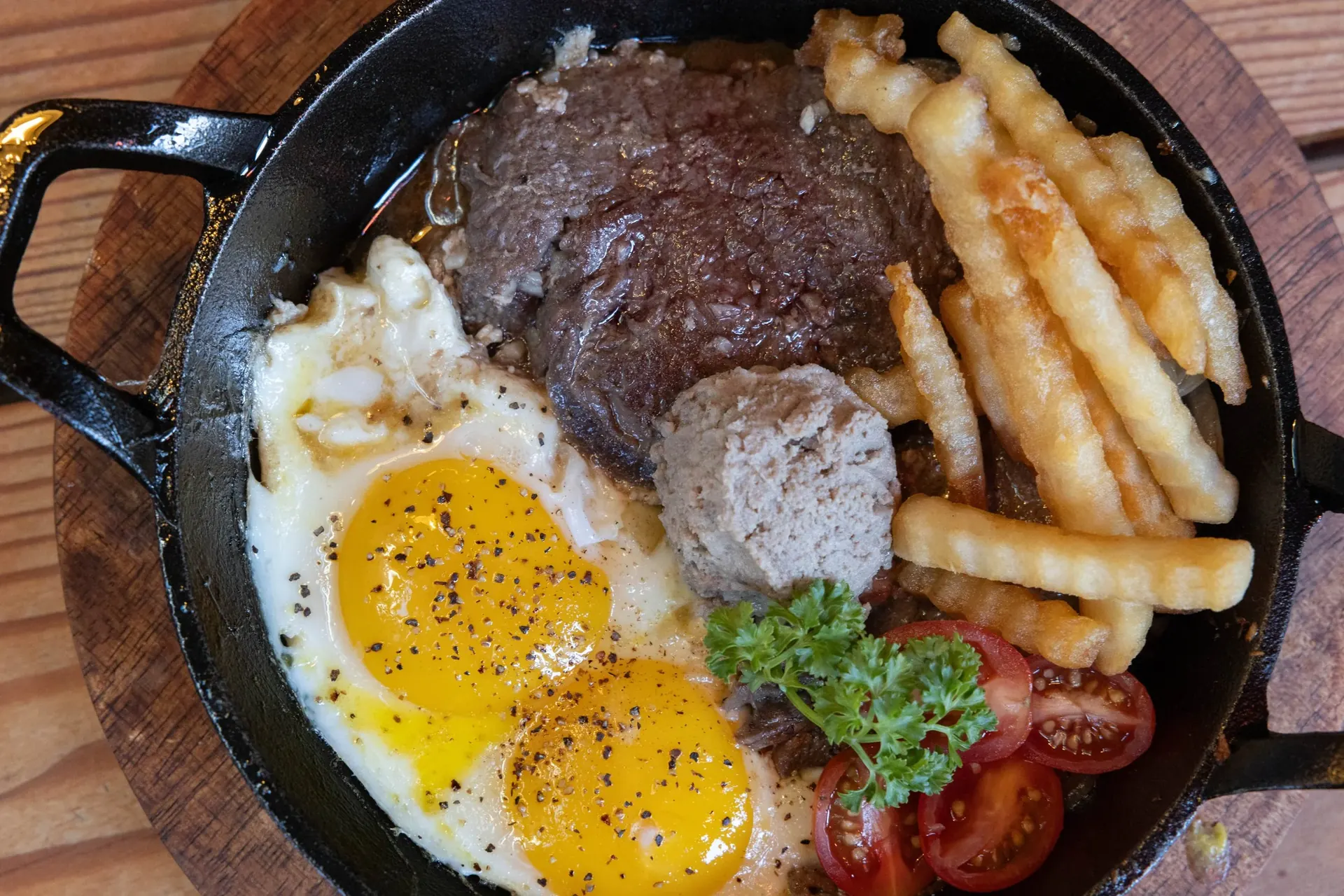 Bò Né — marinated beef tenderloin with sunny side up eggs and pork pâté in a cast iron skillet